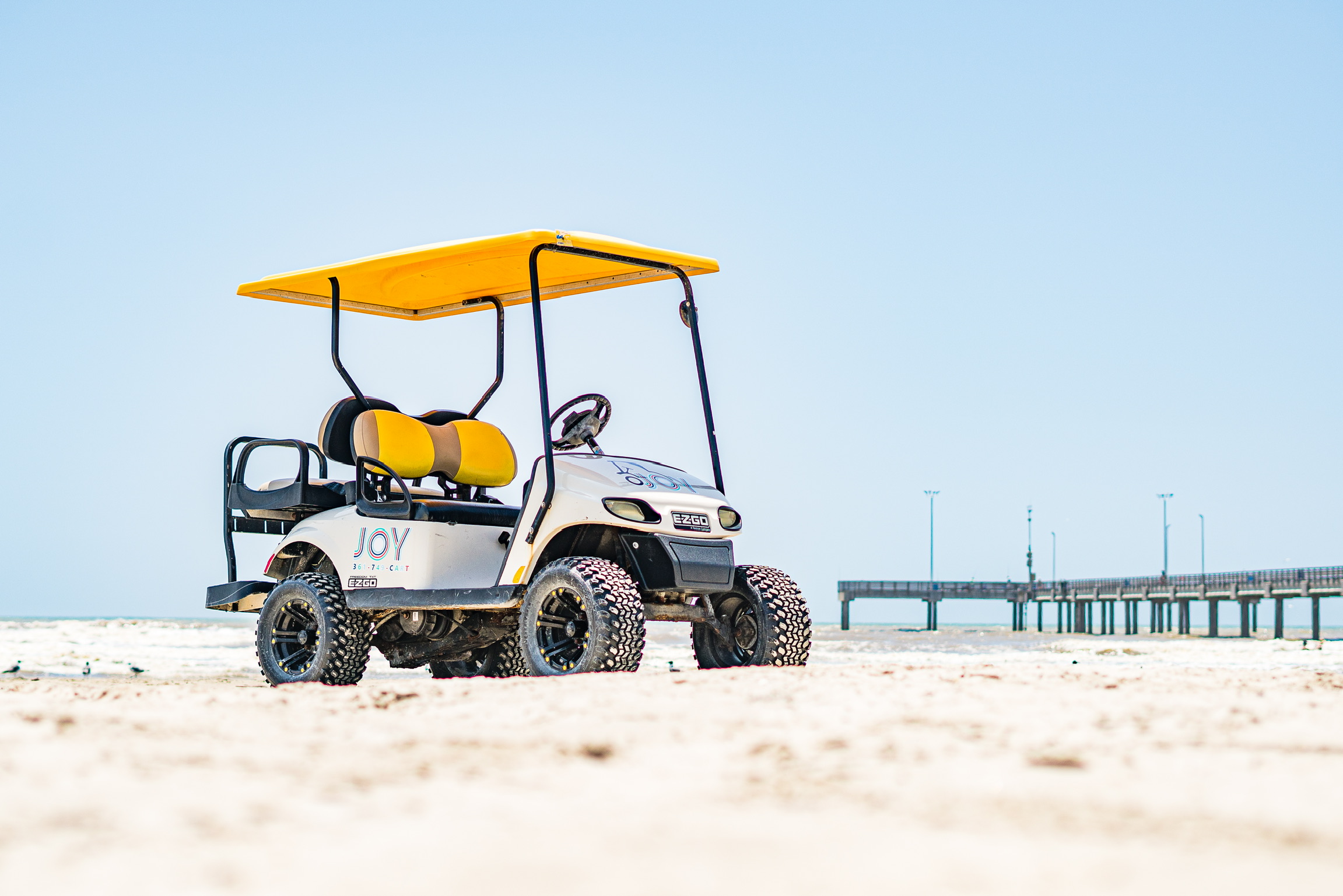 Four passenger E-Z-GO golf cart with yellow roof on Port Aransas beach